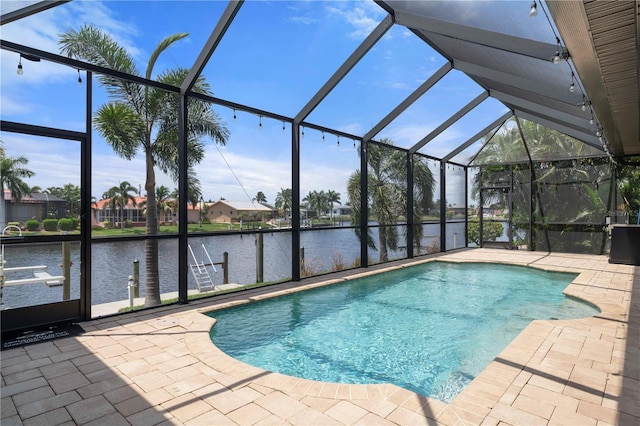 view of pool with glass enclosure, a water view, and a patio area