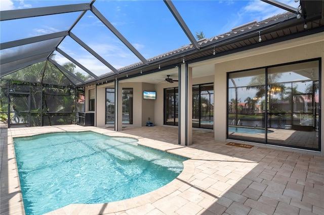 view of swimming pool with glass enclosure, ceiling fan, and a patio area