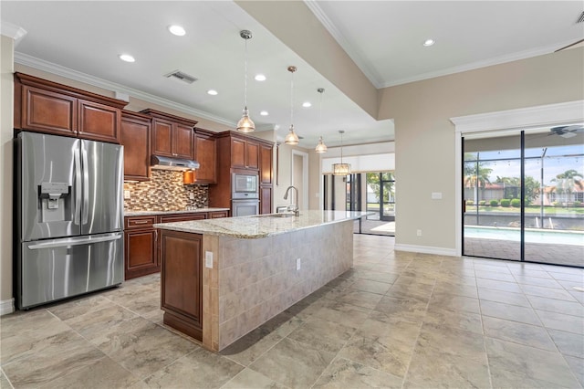 kitchen with appliances with stainless steel finishes, a kitchen island with sink, backsplash, sink, and decorative light fixtures