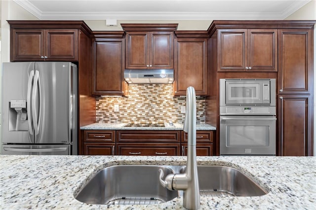 kitchen with appliances with stainless steel finishes, light stone countertops, backsplash, ornamental molding, and sink