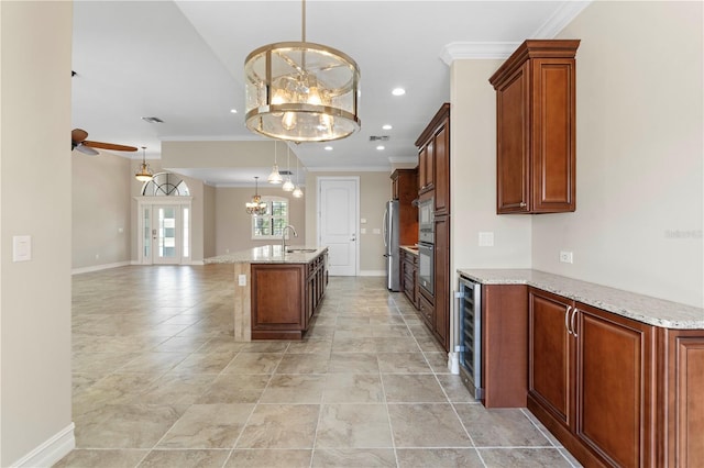 kitchen with wine cooler, a center island with sink, open floor plan, a sink, and ceiling fan with notable chandelier