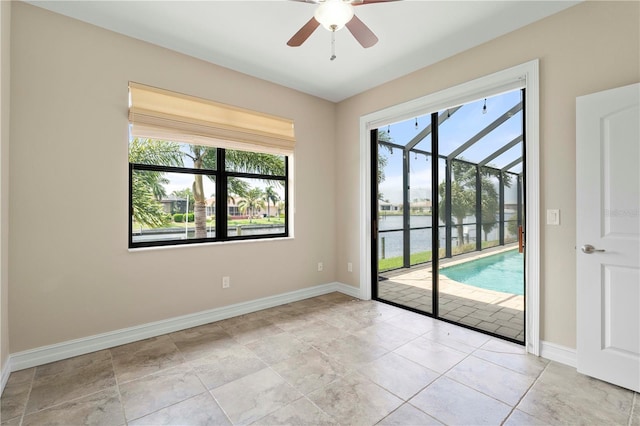 tiled spare room with a water view and ceiling fan