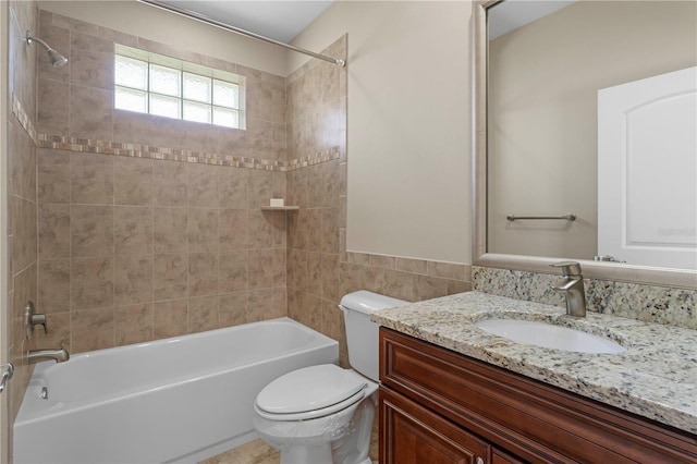 full bathroom featuring vanity, tiled shower / bath, and toilet