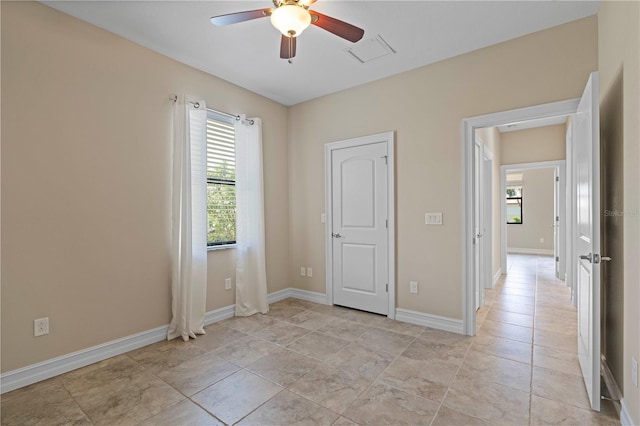 empty room with ceiling fan and baseboards