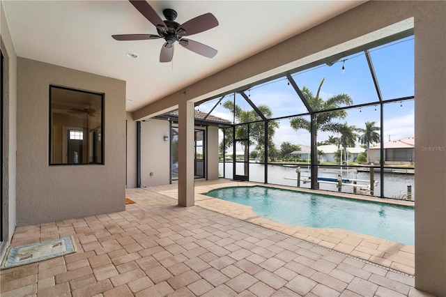 view of pool featuring a patio area, glass enclosure, a water view, and ceiling fan