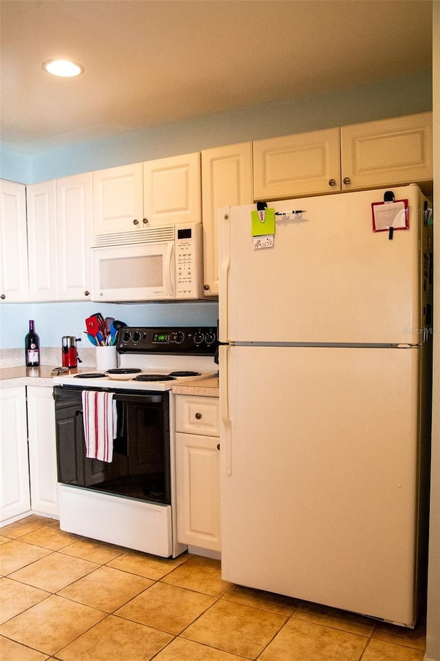 kitchen featuring white appliances, white cabinets, and light tile patterned floors