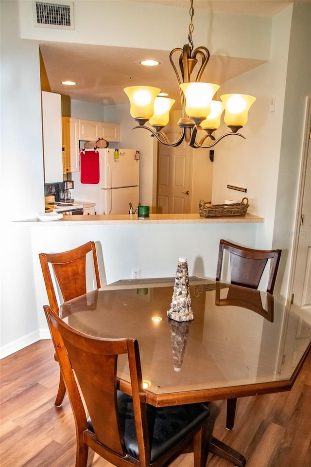 dining area with light wood-type flooring and an inviting chandelier