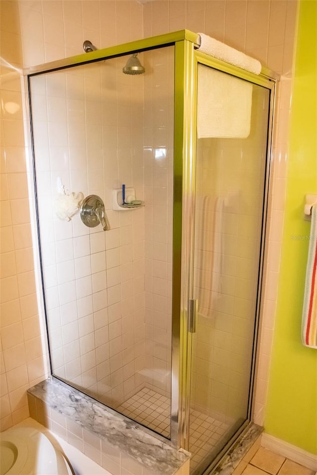 bathroom with a shower with shower door, tile walls, and tile patterned flooring