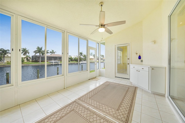 unfurnished sunroom featuring plenty of natural light, ceiling fan, vaulted ceiling, and a water view