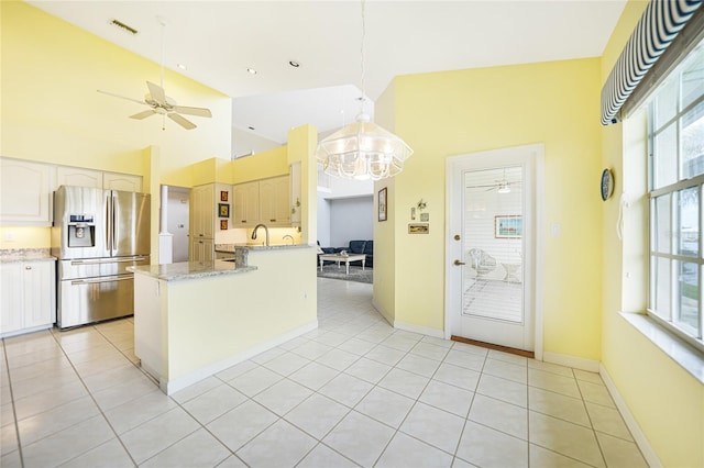 kitchen featuring light tile patterned floors, stainless steel fridge, visible vents, light stone counters, and hanging light fixtures