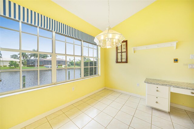 unfurnished dining area with light tile patterned floors, lofted ceiling, a chandelier, and a water view