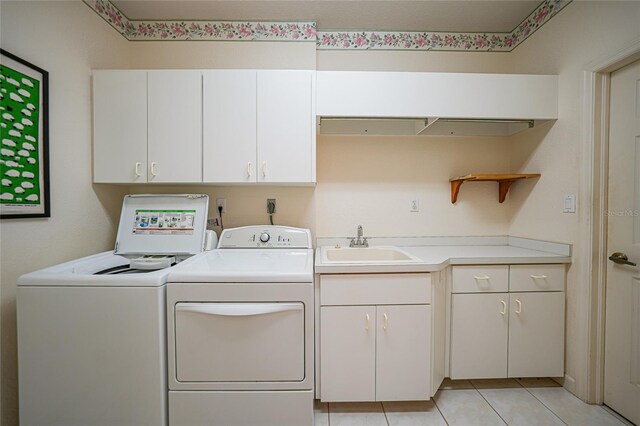 washroom with sink, washing machine and dryer, light tile patterned floors, and cabinets