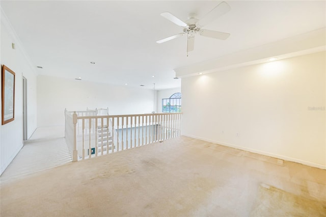 spare room featuring ceiling fan, light carpet, and crown molding