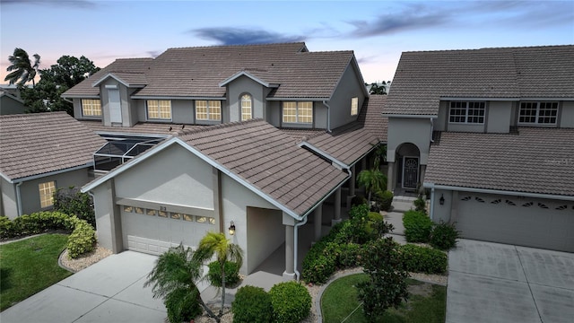 view of front facade with a garage, concrete driveway, a tile roof, and stucco siding