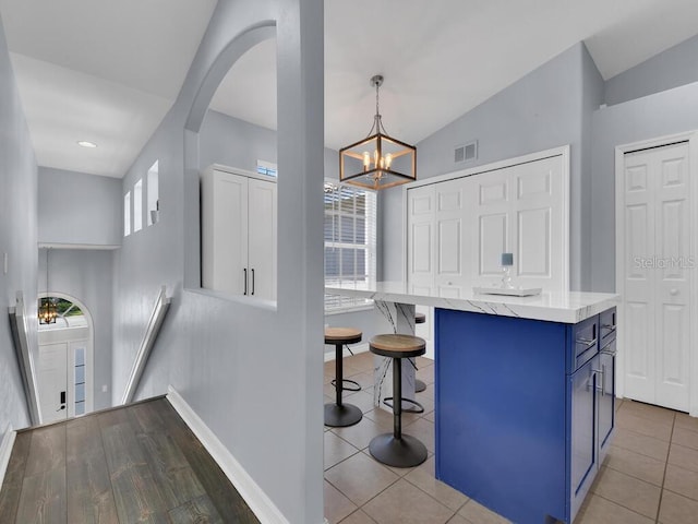 kitchen with pendant lighting, blue cabinetry, a breakfast bar, hardwood / wood-style flooring, and a center island