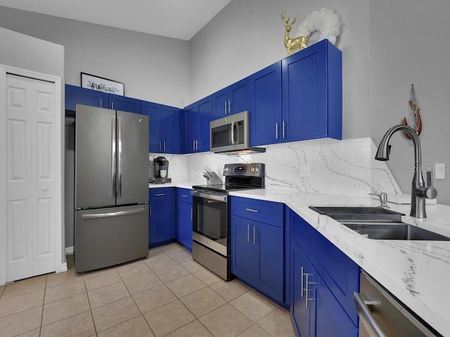 kitchen with backsplash, light stone counters, sink, light tile patterned flooring, and stainless steel appliances