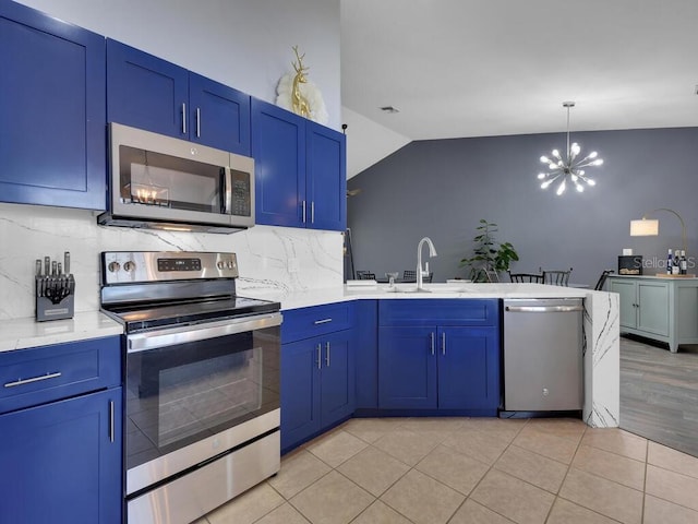 kitchen with appliances with stainless steel finishes, vaulted ceiling, light hardwood / wood-style flooring, and backsplash