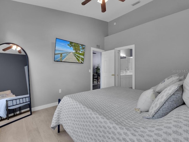 bedroom with a high ceiling, light hardwood / wood-style flooring, ceiling fan, and ensuite bathroom