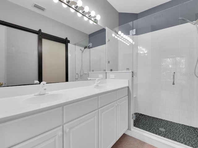 bathroom featuring an enclosed shower, dual bowl vanity, and tile patterned floors