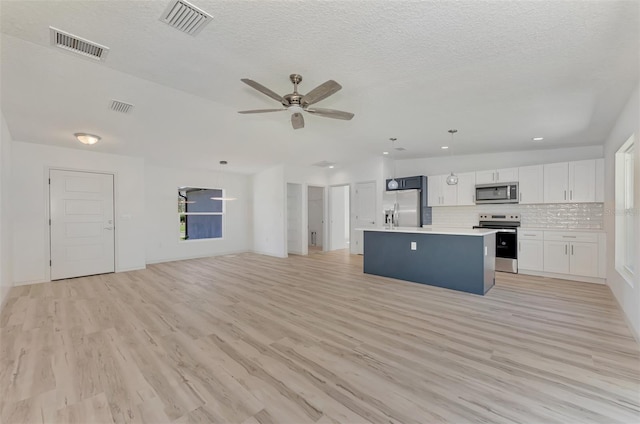 kitchen with stainless steel appliances, white cabinets, light wood-type flooring, a kitchen island, and ceiling fan