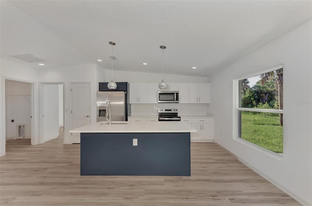 kitchen featuring lofted ceiling, stainless steel appliances, light wood-type flooring, an island with sink, and white cabinetry