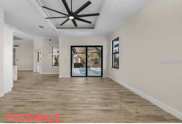 empty room with light hardwood / wood-style flooring and a tray ceiling