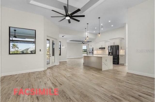 kitchen featuring black fridge with ice dispenser, pendant lighting, an island with sink, ceiling fan, and light hardwood / wood-style flooring