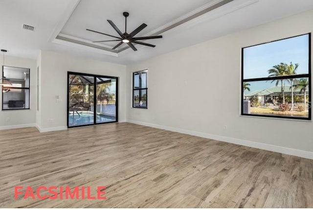 interior space with light wood-type flooring, ceiling fan, and a raised ceiling