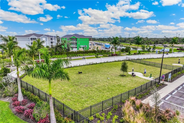 view of home's community with a residential view, a water view, a lawn, and fence