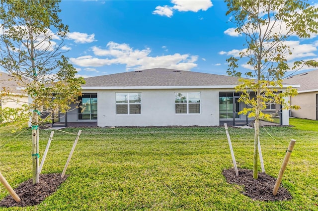 back of property with roof with shingles, a lawn, and stucco siding