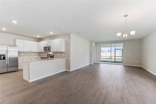 kitchen with decorative light fixtures, light countertops, appliances with stainless steel finishes, open floor plan, and white cabinets