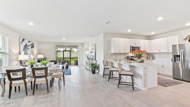 kitchen featuring white cabinets, appliances with stainless steel finishes, light countertops, and a kitchen breakfast bar