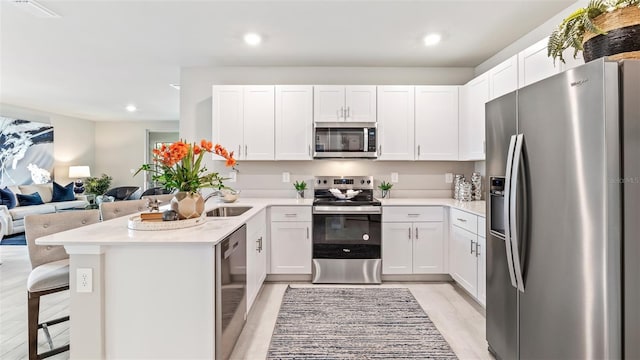 kitchen with stainless steel appliances, open floor plan, light countertops, and a breakfast bar area