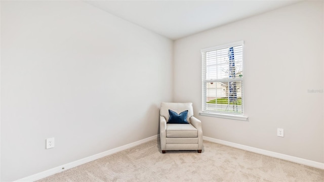 sitting room with baseboards and light colored carpet