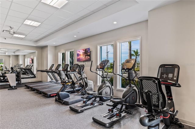 exercise room featuring a tray ceiling, a paneled ceiling, and baseboards