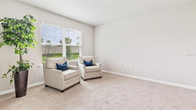 sitting room with baseboards and light colored carpet