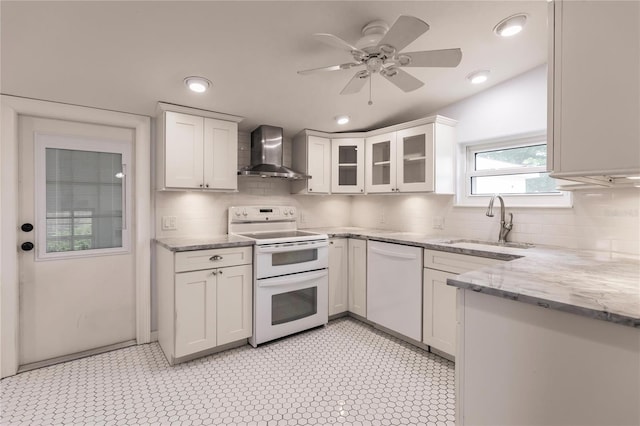 kitchen with white cabinetry, wall chimney exhaust hood, sink, white appliances, and ceiling fan