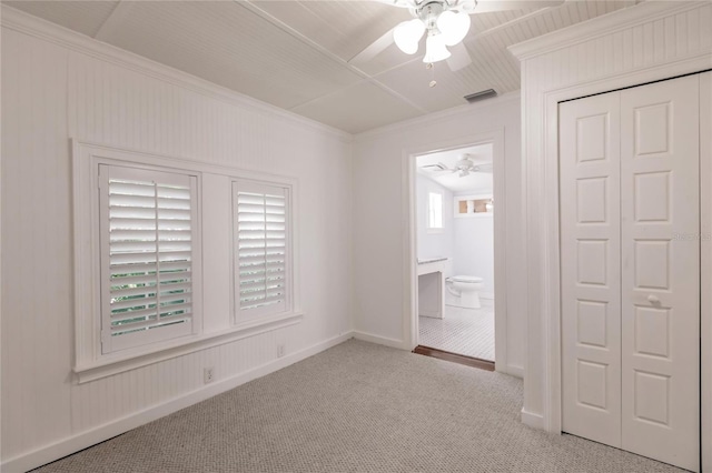 unfurnished bedroom featuring ceiling fan, a closet, light carpet, and ensuite bath