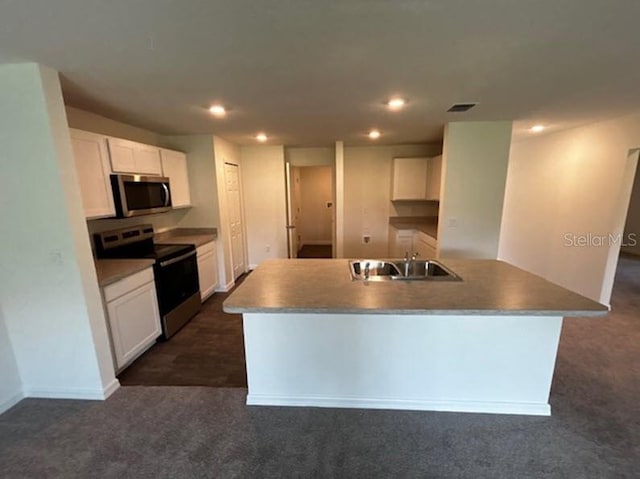 kitchen with white cabinetry, appliances with stainless steel finishes, a kitchen island with sink, dark carpet, and sink