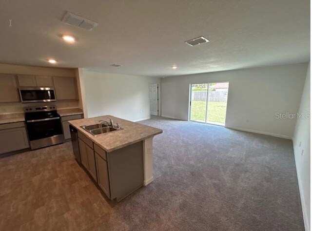 kitchen featuring appliances with stainless steel finishes, a kitchen island with sink, sink, and carpet floors