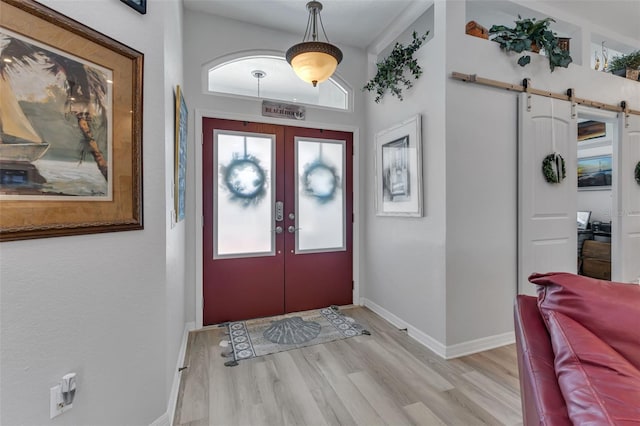 foyer with a barn door, light hardwood / wood-style flooring, and french doors