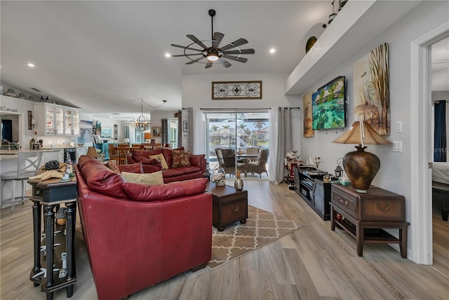 living room with light hardwood / wood-style floors and ceiling fan with notable chandelier