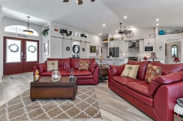 living room with ceiling fan, high vaulted ceiling, light hardwood / wood-style flooring, and french doors