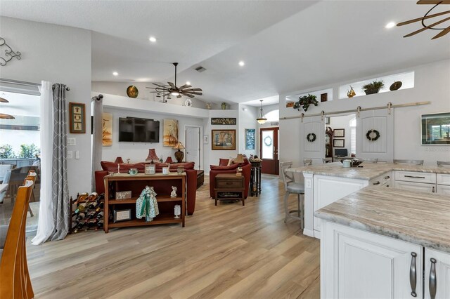 kitchen featuring a barn door, light hardwood / wood-style flooring, a breakfast bar area, and white cabinets