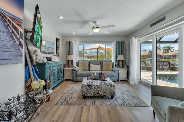 living room featuring hardwood / wood-style floors, ceiling fan, and a textured ceiling