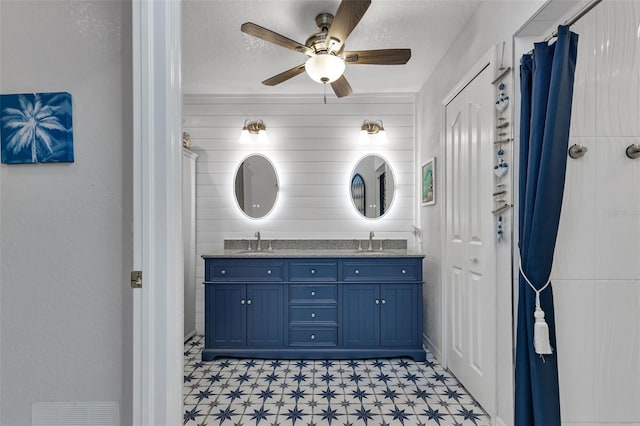 bathroom featuring ceiling fan, tile patterned flooring, a textured ceiling, and dual bowl vanity