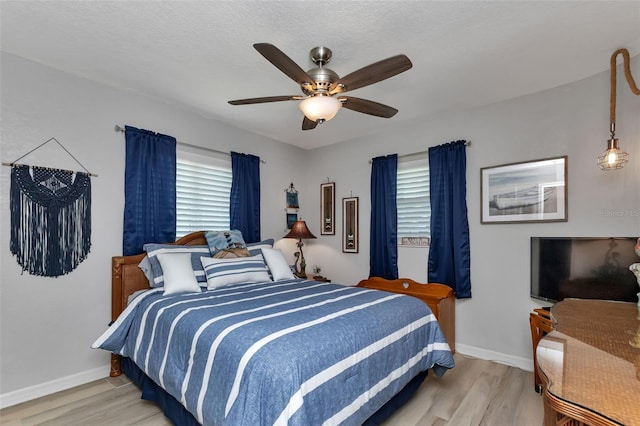 bedroom featuring ceiling fan, light hardwood / wood-style floors, and a textured ceiling