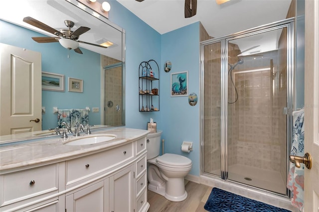 bathroom with ceiling fan, a shower with door, toilet, vanity, and hardwood / wood-style flooring