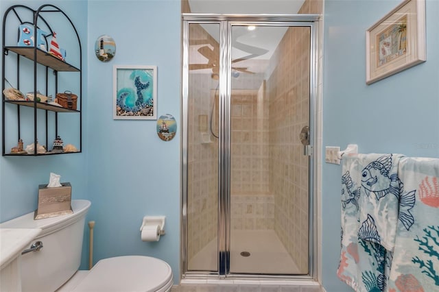 bathroom featuring toilet and a shower with door