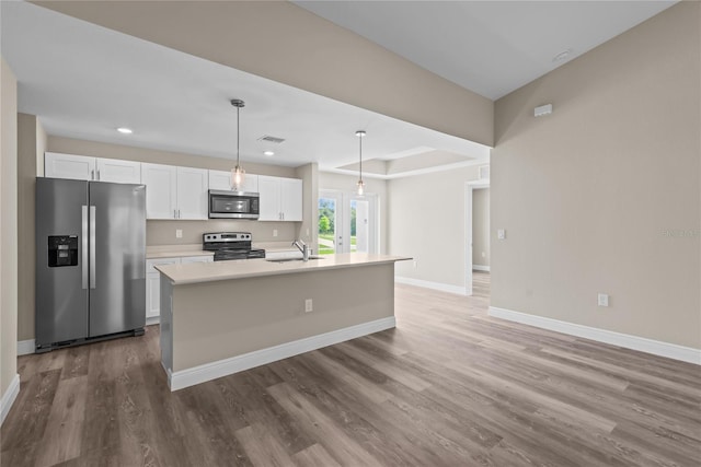 kitchen featuring white cabinets, appliances with stainless steel finishes, decorative light fixtures, and an island with sink